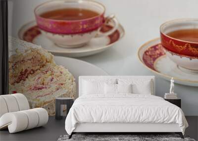 delicious meringue roll with strawberry cream and vintage cups of tea on a white glass surface Wall mural