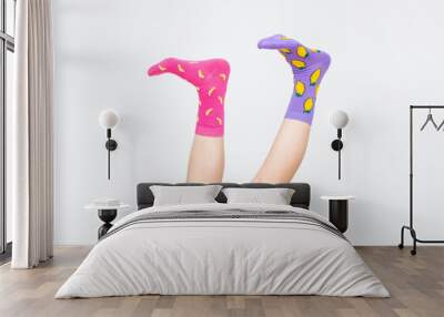 female legs in colorful socks holding banana juggling feet isolated on white background Wall mural