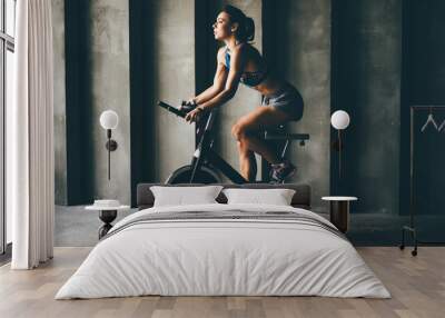 Attractive young woman at the gym riding on spinning bike. Healthy Lifestyle and Sport Concepts. Wall mural