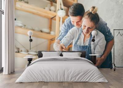 Couple in love working together on potter wheel in craft studio workshop. Wall mural