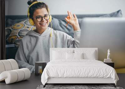 Millennial woman having video call on her computer at home. Smiling girl studying online with teacher. Wall mural