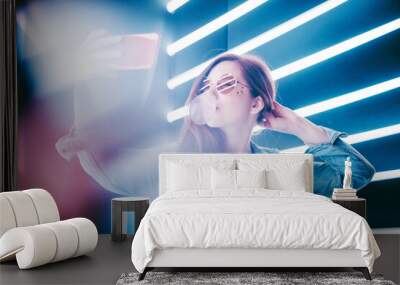 Portrait of modern young woman making selfie at the neon light. Wall mural