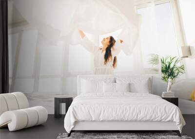 Woman making bed in the sunny morning. Woman doing morning routine. Wall mural