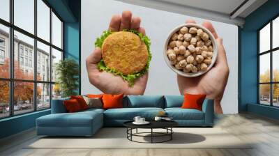 man’s hands hold plant based non meat burger(cutlet) and white bowl with chickpeas. The concept of healthy and vegetarian food. Wall mural