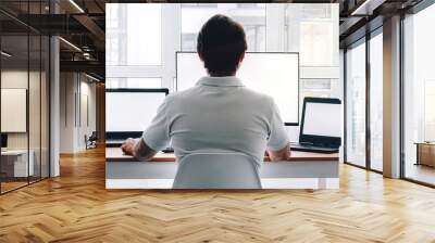 Man sitting at workplace with two laptops and monitor near the window. Remote work from home Wall mural