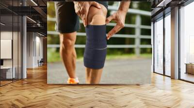 Athletic Man with Knee Brace Preparing for Outdoor Running Wall mural