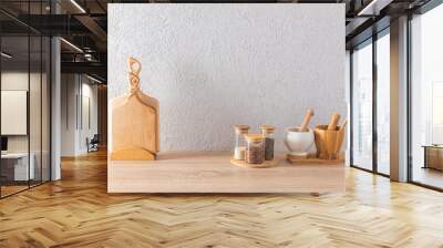 A set of glass spice jars, two mortars with a pestle, cutting wooden boards on the kitchen countertop. minimalism in the interior of a modern kitchen. Wall mural