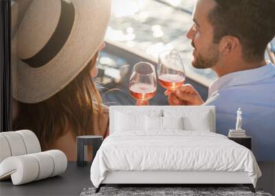 Drinking wine on yacht at sea. Romantic traveling at sunset. Happy couple in love with wineglasses enjoying summer vacation, celebration. Intimate lifestyle moment. Relaxed man and woman on sailboat Wall mural