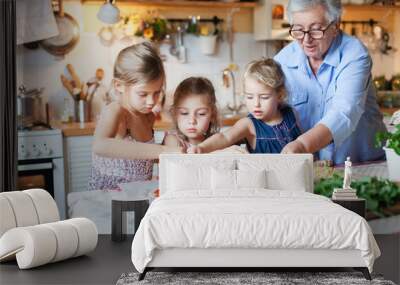 Family, kids cooking pizza in cozy home kitchen. Grandmother and three sisters, her granddaughters preparing homemade italian food. Funny little girls are helping senior woman. Children chef concept. Wall mural