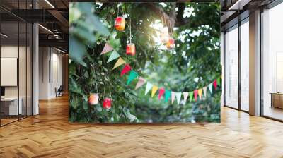 Garland of colorful flags and homemade flashlights at sunset in summer garden. Concept of celebration Happy Birthday party. Paper festive decoration outdoor. Wall mural