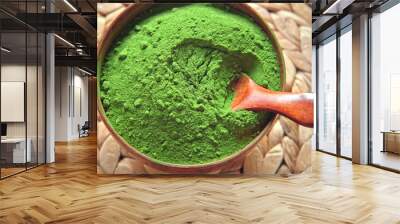 Wooden spoon with powdered matcha tea in a bowl spinning on natural background. Matcha powder. Top view, Closeup. Finely ground green powder. Japanese culture. Healthy eating with high antioxidants. Wall mural