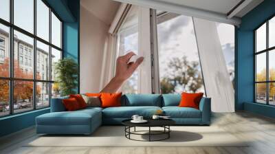 One sided open window. A hand opens a vinyl plastic window on a blue sky background. Wall mural