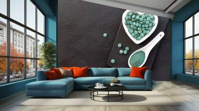 Green algae in powder and pills - chlorella, spirulina a black background. Healthy green food supplement concept. Wall mural