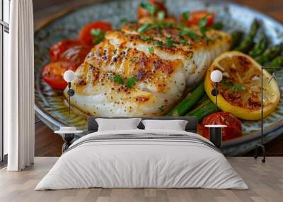 A piece of baked white fish rests on a plate among asparagus, tomatoes, lemon and herbs Wall mural