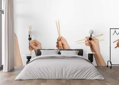 A set of female hands holding wooden chopsticks for sushi or rolls on a blank background. Wall mural