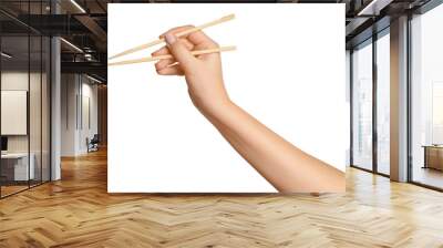 A woman's hand holds wooden chopsticks for sushi or rolls on a blank background. Wall mural