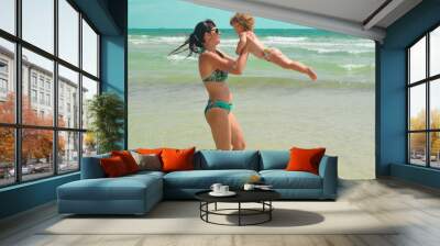 Mother and her daughter have summer vacation on the sea lifestyle. Motherhood on the beach in sunny day Wall mural