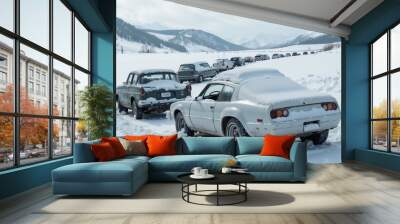 Snow-covered vintage cars stuck in a snowy landscape with mountains in the background Wall mural