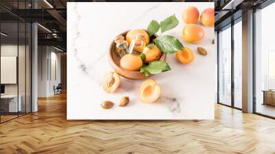 two glass bottles with cork lid with apricot oil and ripe apricots in a wooden bowl on a marble background. rejuvenation. skin care. Wall mural