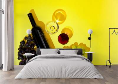 Two glasses of red and white wine, a bottle, grapes on a yellow background. The concept of Italian wine. Photo with hard shadows, top view. Banner, long format. Free space for text Wall mural