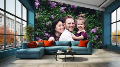 cheerful happy family hugging near lilac flowering bushes Wall mural