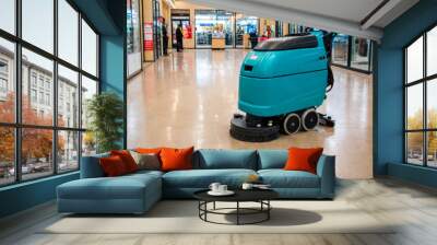 Big industrial scrubber dryer machine on glossy floor of shopping mall with various shops and bright storefronts, deserted. Without worker. Soft diffused lighting. On blurry background. Copy space. Wall mural