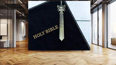 Ancient sword on top of Christian holy bible book. Top view. Close-up. Biblical concept of spiritual power, strength, obedience and studying the word of God Jesus Christ. Wall mural