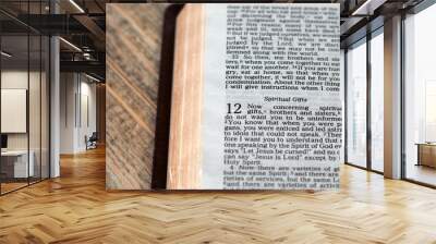 Christian verses about spiritual gifts in open holy bible book with golden pages on wooden table. Close-up. Wall mural