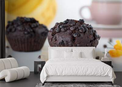 Moist chocolate chip muffin with banana with baking paper on a white background. Sweet fluffy brown cupcake for breakfast, dessert, or snack. Delicious vegan bakery. A close-up. Wall mural