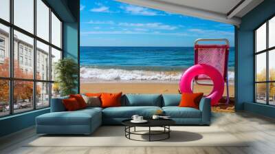 Summer beach holiday concept. A chair and an inflatable swimming ring on sand of beach against the backdrop of the sea and blue sky Wall mural