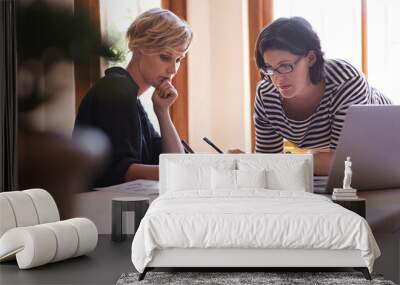 A successful business comes with a lot of hard work. A cropped shot of two focused women working together in a home office. Wall mural