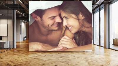 Couple, happy and love in bed, waking up and bonding in a bedroom together, flirting and romantic. Romance, man and woman relax, intimate and resting at hotel for valentines day, anniversary or bond Wall mural