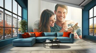 Couple, kitten and smile in home with care, hug and love for bonding with pet in living room. People, man and woman with kindness, portrait and excited for cat in lounge for animal adoption at house Wall mural