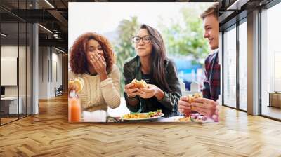 Good food and laughter go hand-in-hand. Cropped shot of three friends eating burgers outdoors. Wall mural