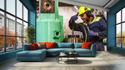 A close-up of the upper body and head of a marine engineer officer, wearing a helmet, focused on performing duties in the engine room during the repair of the ship’s main engine. Wall mural