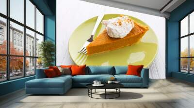 Slice of pumpkin pie with whipped cream over white wooden background Wall mural