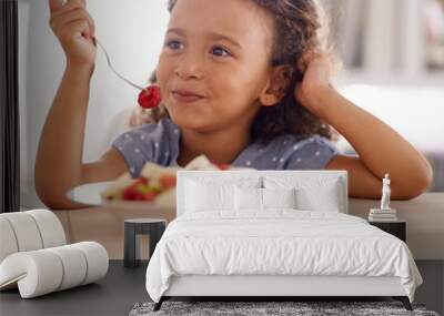 Who knew it would be so yummy. Shot of a cute little girl eating fruit salad at a table. Wall mural