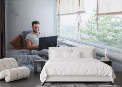 Man working in bed on laptop early in the morning Wall mural