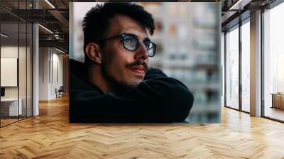 Portrait of a young man looking at sunset from a balcony thinking about life Wall mural