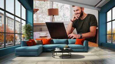 Young casual man working on a laptop Wall mural