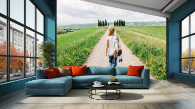 Young female traveler walking in Tuscany countryside Wall mural