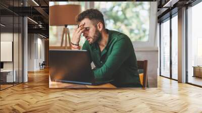 Young man having stressful time working on laptop Wall mural