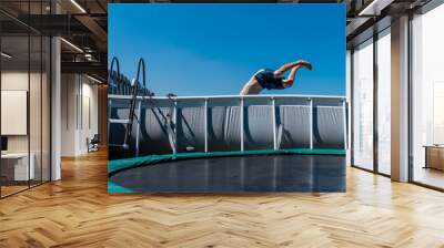 Boy is jumping in a swimming pool in the garden  Wall mural