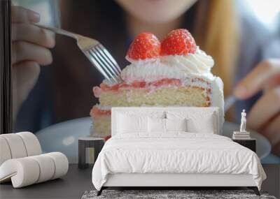 A young Asian woman eating a slice piece of chiffon strawberry layer cake sitting at a table, eating a sweet or dessert cake. Healthy fast food unhealthy choice concept. Wall mural