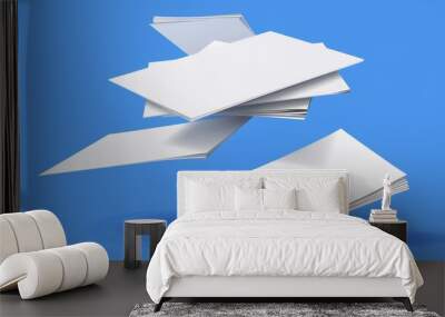 An illustration of flying white paper sheets from a stack of documents. Modern realistic illustration showing a chaotic flight of blank note pages on the wind in front of a blue background. Office Wall mural