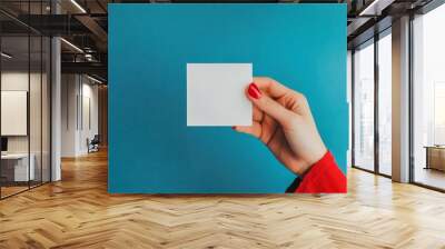 Business concept with woman holding blank white card on blue background. Wall mural