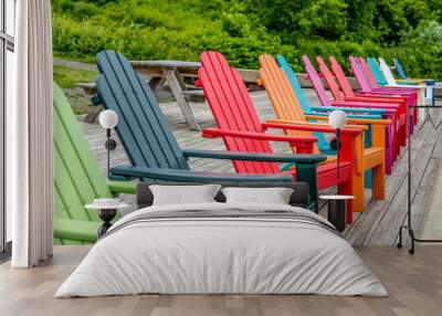 Colorful Wood Adirondack Chairs Lined Up on a Dock Overlooking a River Wall mural