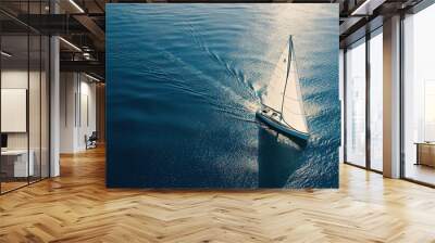 An aerial photo of a sailing yacht in the open sea, with the boat set against the clear blue ocean. Concept for ocean travel and adventure. Wall mural