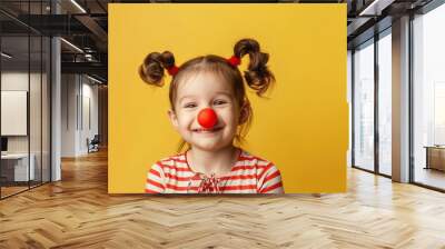 Happy clown with a red nose. Cheerful little girl on a yellow background. April Fool's Day. Wall mural