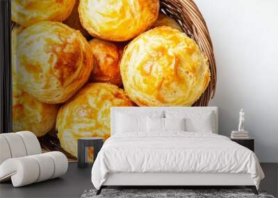 On a white table, a basket full of cheesy biscuits sits alongside a steaming coffee Wall mural